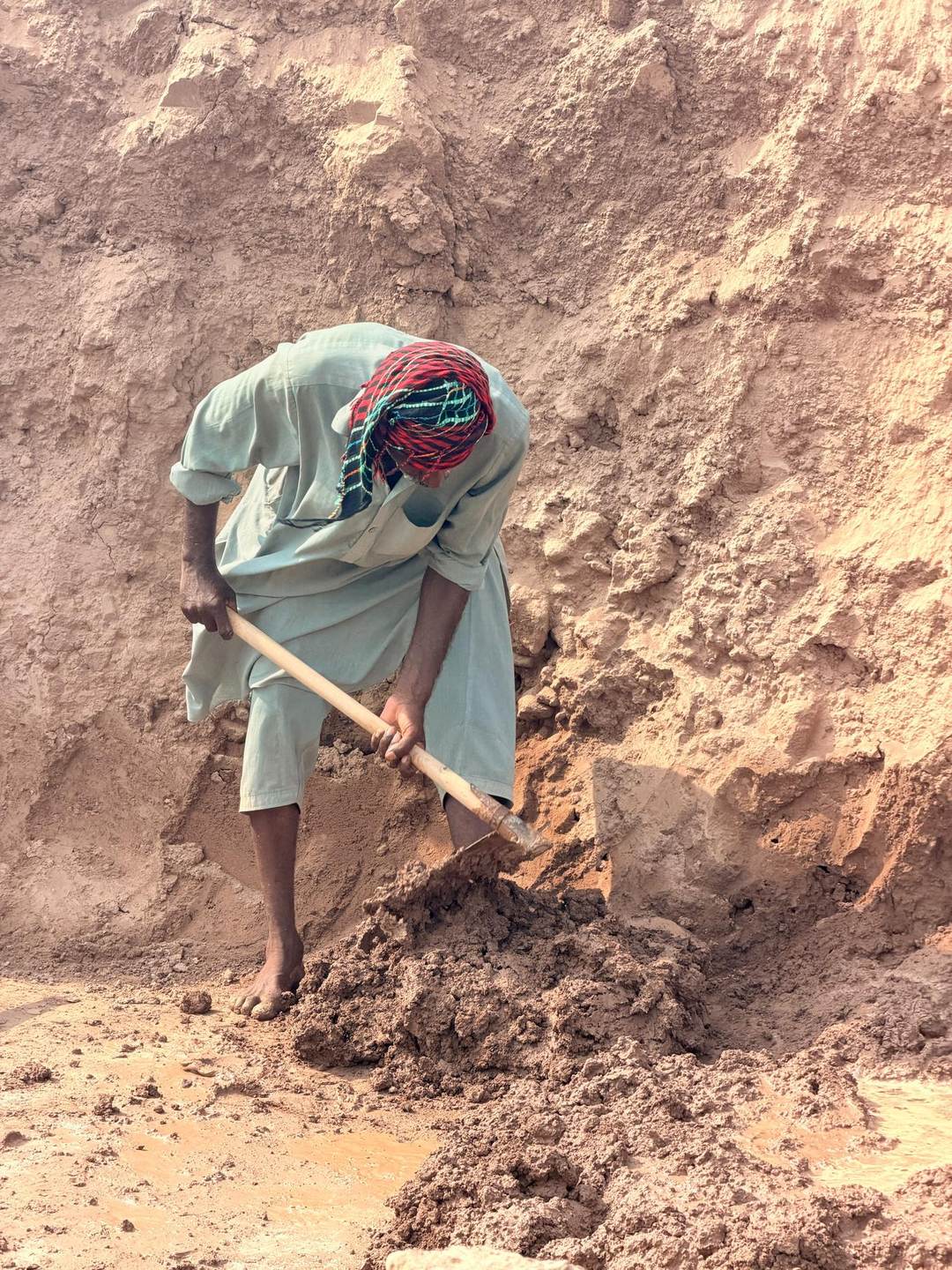 Aruf Masih digging clay by hand from a pit at the brick kiln