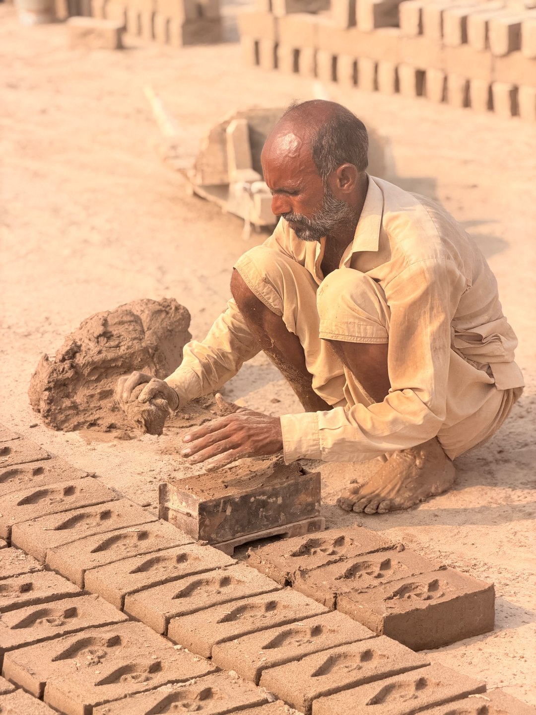 Javed Masih presses clay into a brick mold